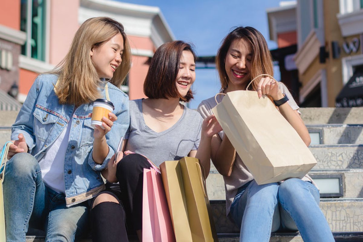 Three friends laughing with shopping bags