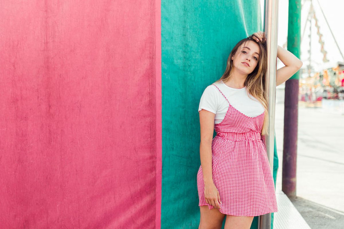 Woman leaning on a colorful pink and teal wall